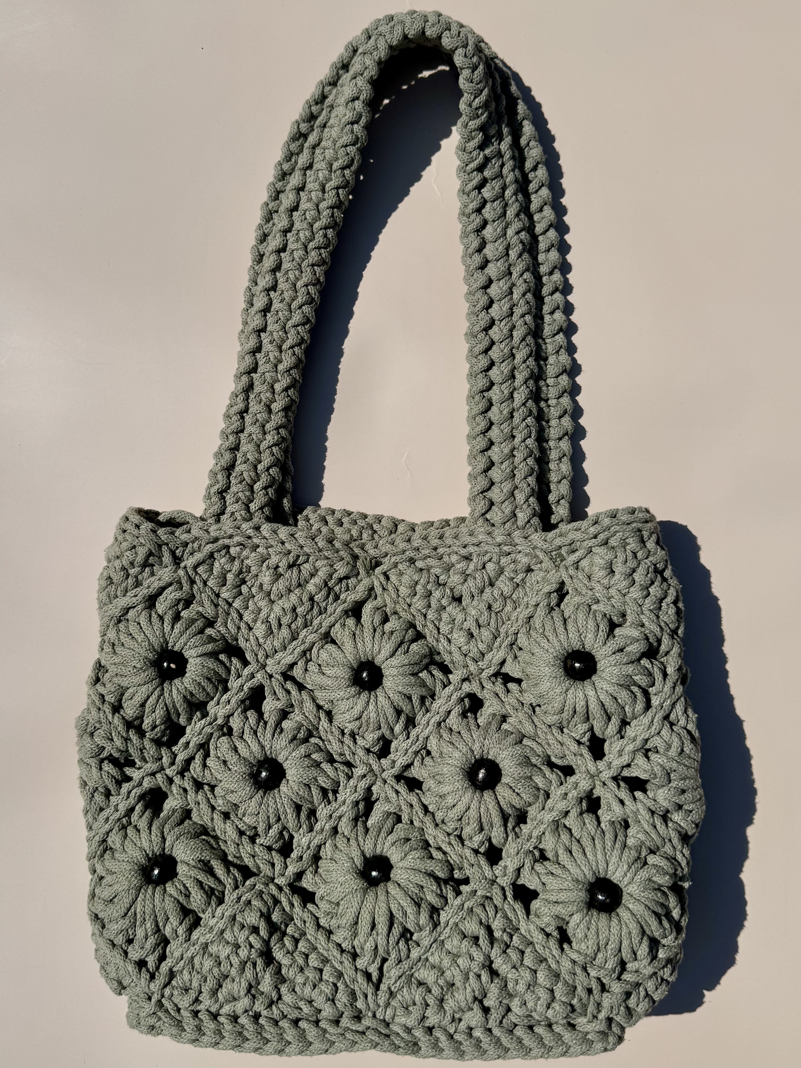 AUGU crochet bag laid on a warm neutral surface